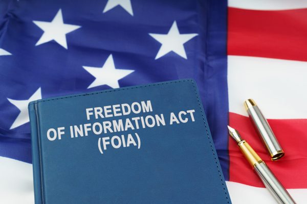 Law concept. On the US flag lies a pen and a book with the inscription - FREEDOM OF INFORMATION ACT - FOIA